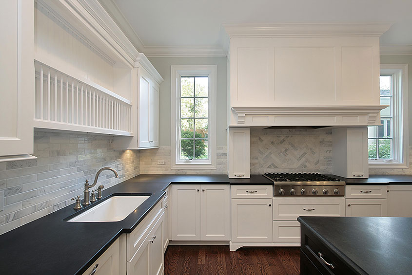 black granite counter with white cabinets and a stove